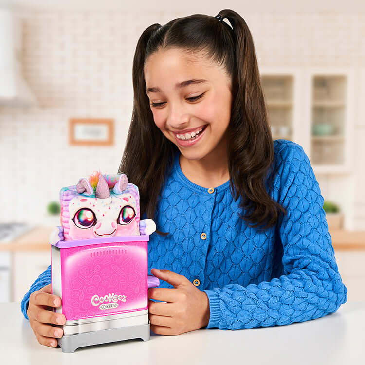 Girl excitedly reveals a plush friend from the Cookeez Makery Toastie Treatz Toaster, showcasing the surprise and joy of this toy.