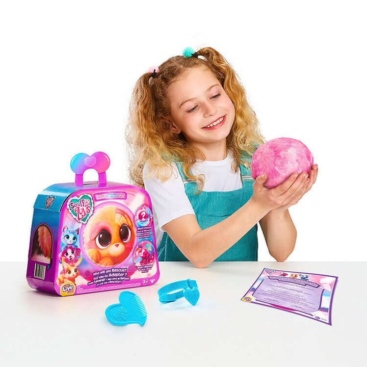 Girl smiling while holding a Scruff-a-Luvs Neon Pets pack with grooming comb and instructions on the table.