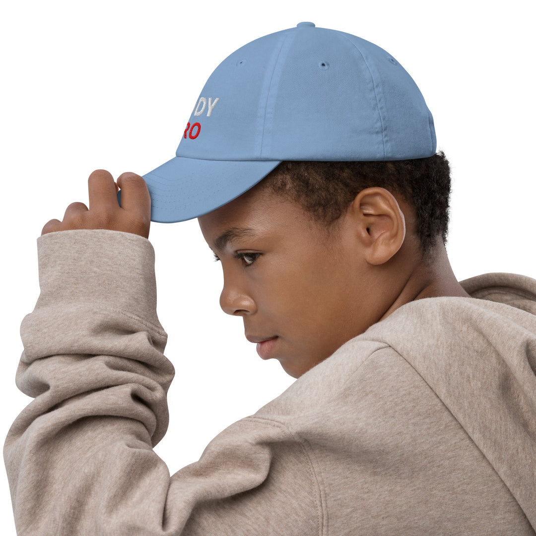 A young boy adjusting his Oddy Pro Youth baseball cap, showcasing its stylish design and fit.